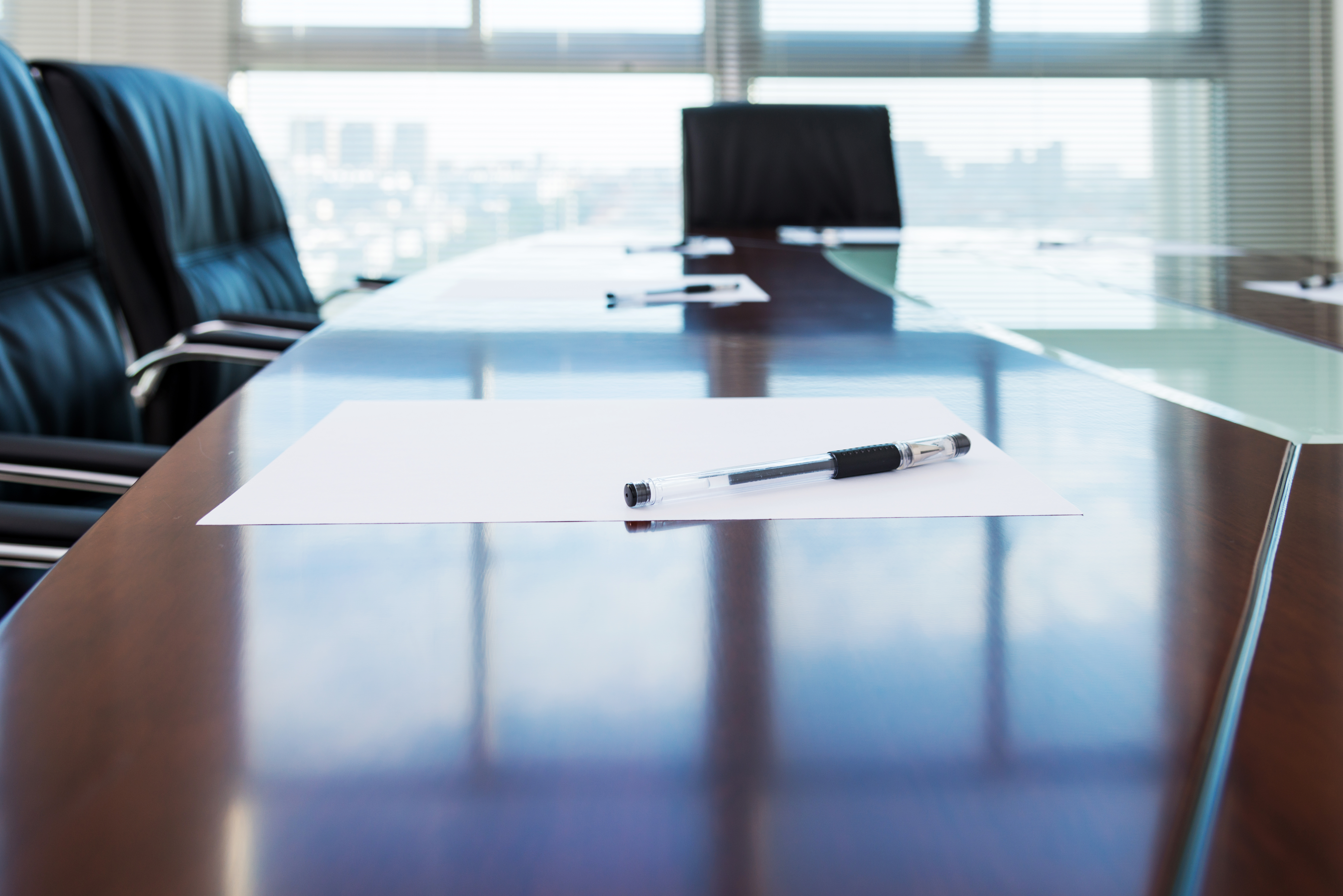Corporate boardroom with blank paper set for the meeting.