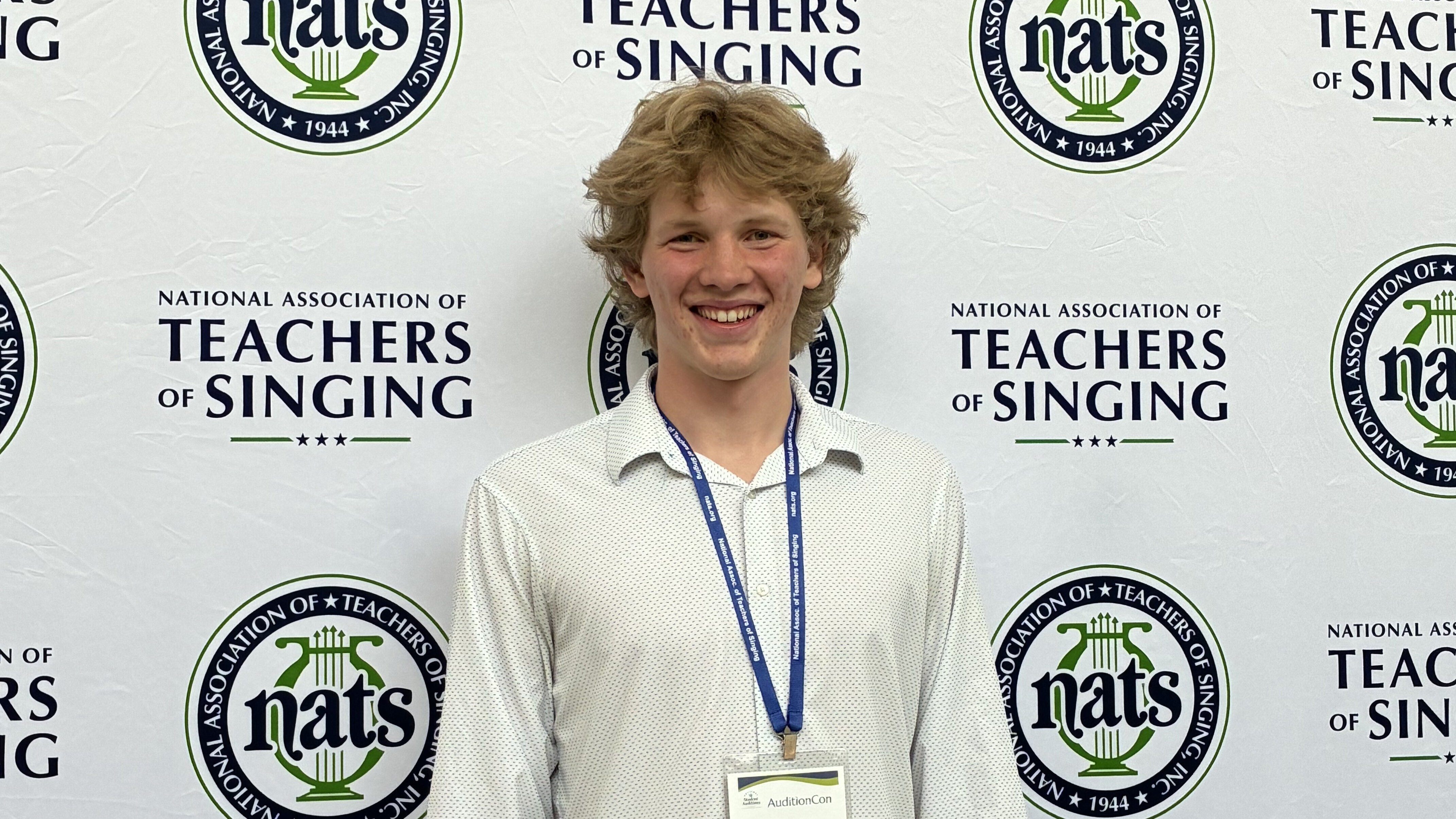 Luke Palau standing in front of a banner at singing competition.