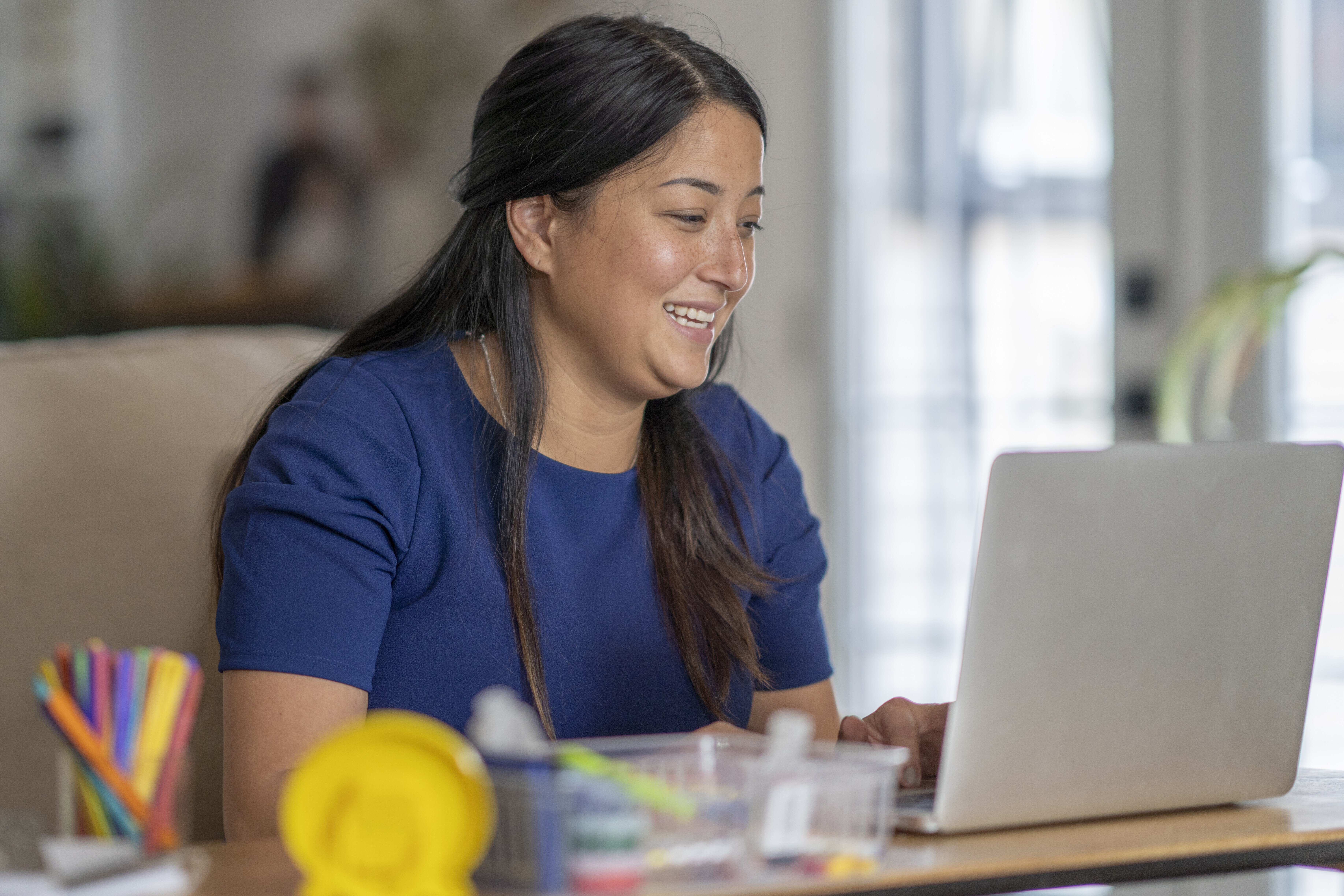 Female teacher working from home, using video chat to connect with her students during the COVID-19 pandemic.