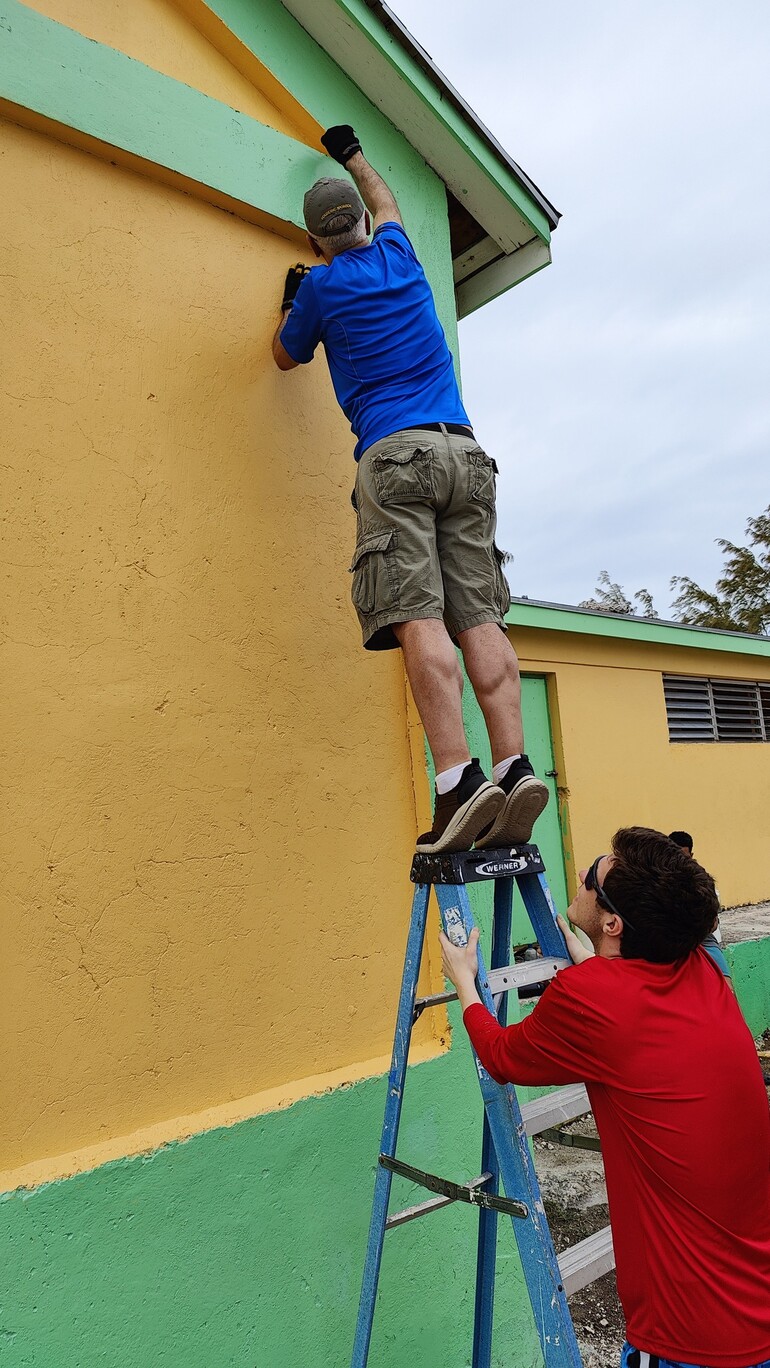 People painting an exterior wall a bright color