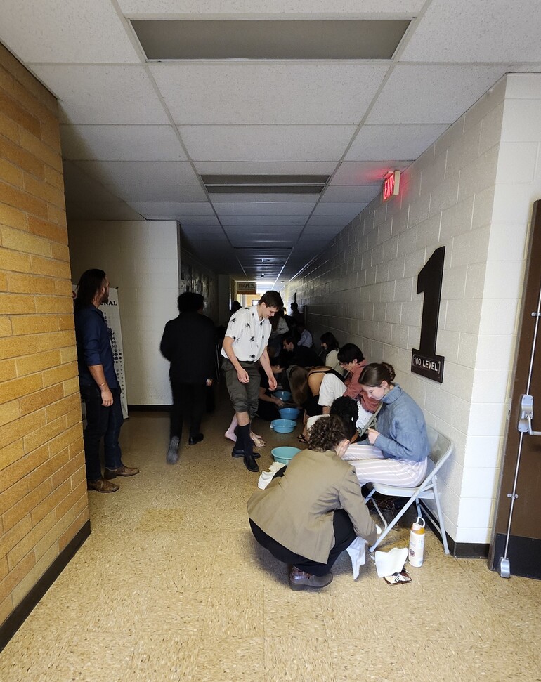 Students line hallway to wash feet in communion service.