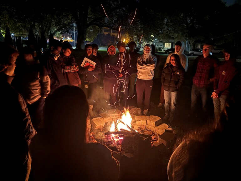 Students stand around bonfire