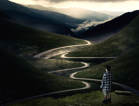 Man looking at empty road through a valley.