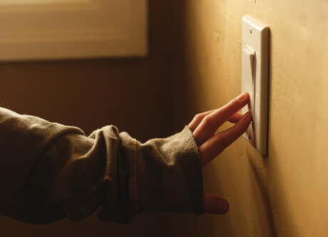 Hand turning on light switch.