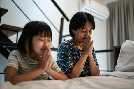 Mother and daughter praying at home