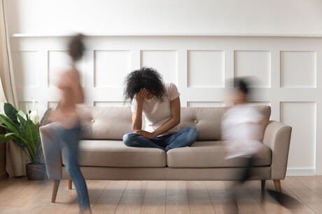 Frustrated stressed single mom having headache feel tired annoyed about noisy active kids playing at home, upset disturbed black mother fatigued of difficult disobedient misbehaving children