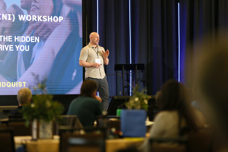 man speaks to audience from a stage