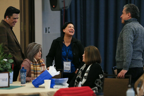 five people stand and sit while talking and laughing