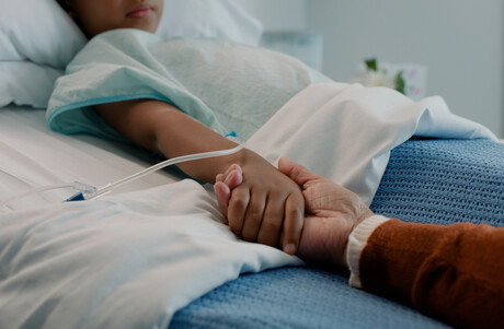 Hospital scene with an adult holding a child's hand