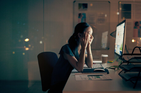 A young businesswoman stares at a screen with fatigue