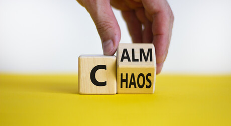 Stop chaos, time to calm. Male hand turns a wooden cube and changes the word 'chaos' to 'calm'.