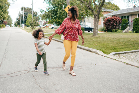 Mom and daughter walking together through the neighborhood.