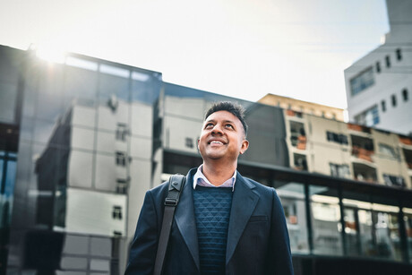 Shot of a businessman standing in the city and looking up hopefully