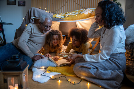 Grandparents and grandchildren enjoying a moment in a homebuilt fort tent.