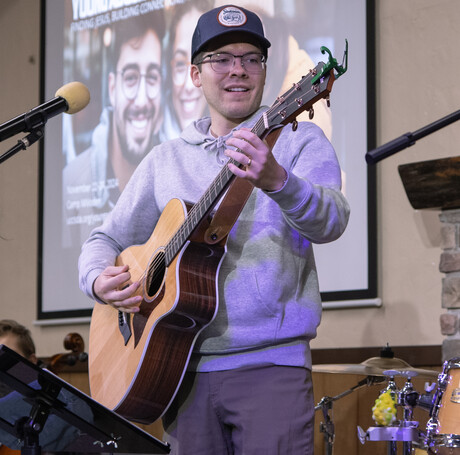 Pastor Isaac Peterson playing guitar for worship.