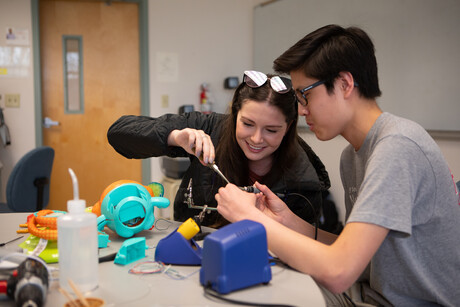 Two students work together on wiring a children's toy.