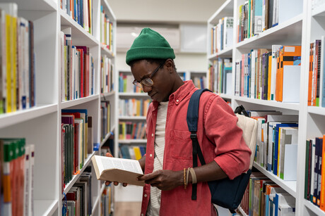 Curious reader looking at a book in a library aisle