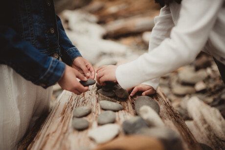 Little girls stacking stones on a piece of driftwood at the beach