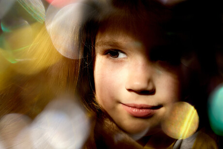 Close up dreamy face of pretty little child girl with xmas lights bokeh.