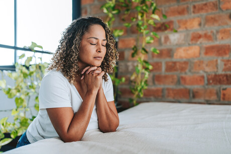 Woman kneeling praying in her room