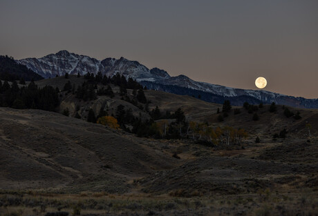 Full moon setting over mountains west of Gardiner, MT.
