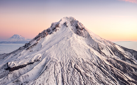 Mount Adams rises above the clouds at sunrise behind Mount Hood.