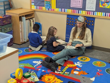 Students reading with the teacher’s aide