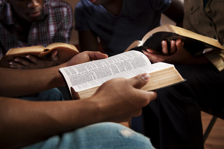 Young adults meeting together in a Bible study.  Focus on the Open Bible.