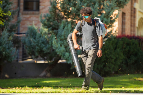 Grounds worker student using a leaf blower