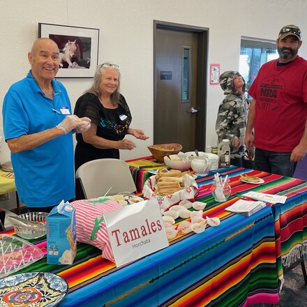 Smiling people serving vegetarian Mexican food.