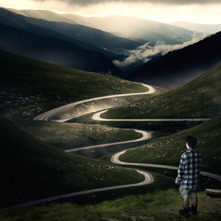 Man looking at empty road through a valley.