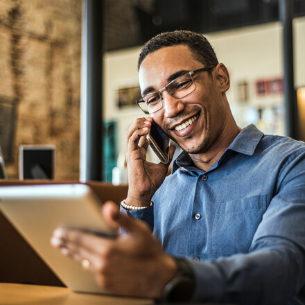 A man talks on phone while holding a tablet.