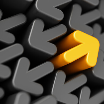 One yellow arrow pointing back in a sea of grey arrows pointing in the opposite direction.