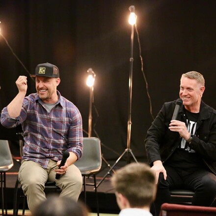 two men sitting on stage with microphones