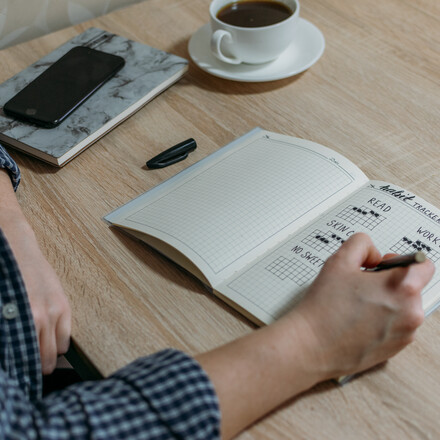 Bullet Journal Habit Tracker. Woman cross off day with routine in her Habit Tracker. Selective focus.