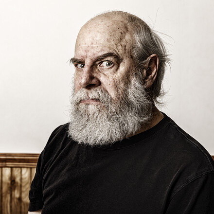 Grumpy, angry old bearded senior adult man curmudgeon frowning and staring sidelong at the camera.