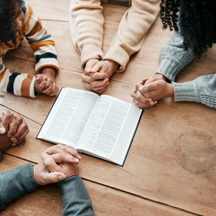 Bible, reading book or hands of family in prayer, support or hope in Christianity home for worship together. Mother, father or grandparents studying, praying or learning God in religion with children