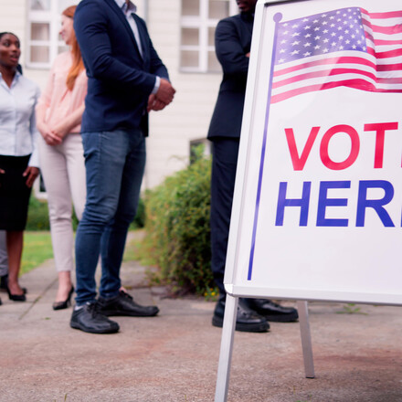 Diverse People At Voting Booth. Vote Here Elections Sign
