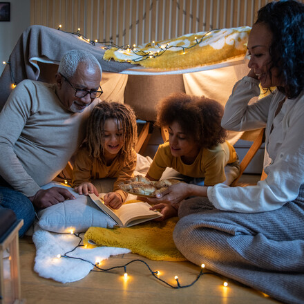 Grandparents and grandchildren enjoying a moment in a homebuilt fort tent.