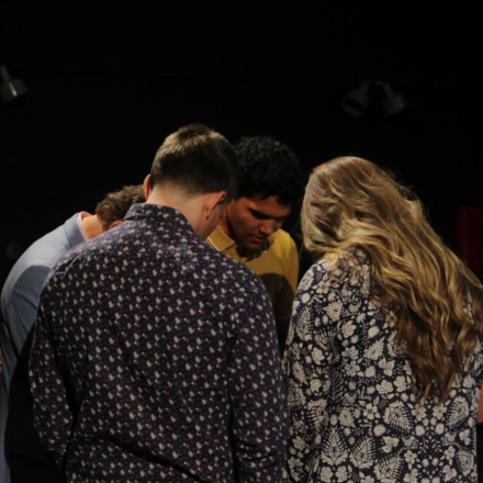Student pray together in a group, heads bowed.