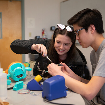 Two students work together on wiring a children's toy.