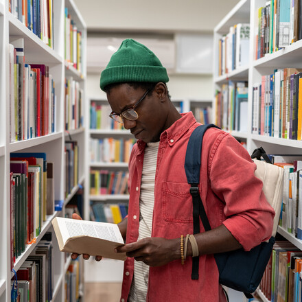 Curious reader looking at a book in a library aisle