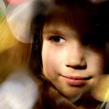 Close up dreamy face of pretty little child girl with xmas lights bokeh.