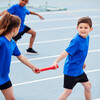 Children In Athletics Team Competing In Relay Race On Sports Day