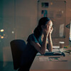 A young businesswoman stares at a screen with fatigue