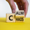 Stop chaos, time to calm. Male hand turns a wooden cube and changes the word 'chaos' to 'calm'.