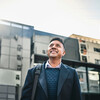 Shot of a businessman standing in the city and looking up hopefully