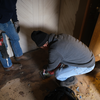 Two volunteers with power tools work to replace old flooring.