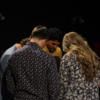 Student pray together in a group, heads bowed.