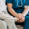 A female nurse caregiver holds hands to encourage and comfort an elderly woman. For care and trust in nursing homes for people of retirement age Caregiver helping elderly woman provides medical advice